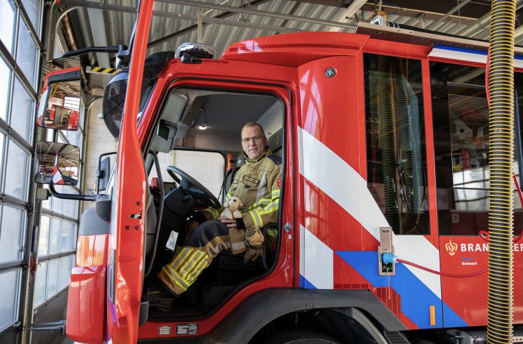 Brandweerman leest uit het Friese prentenboek 'Stip yn 'e brânspuitauto' voor aan kinderen in de bibliotheek van Makkum.