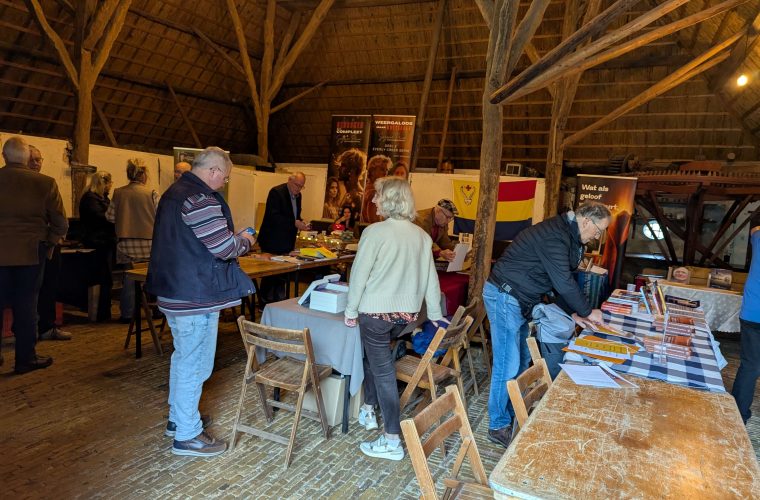 Boekenbeurs in Allingawier met boekenplanken en bezoekers in de Kerkbuurt.